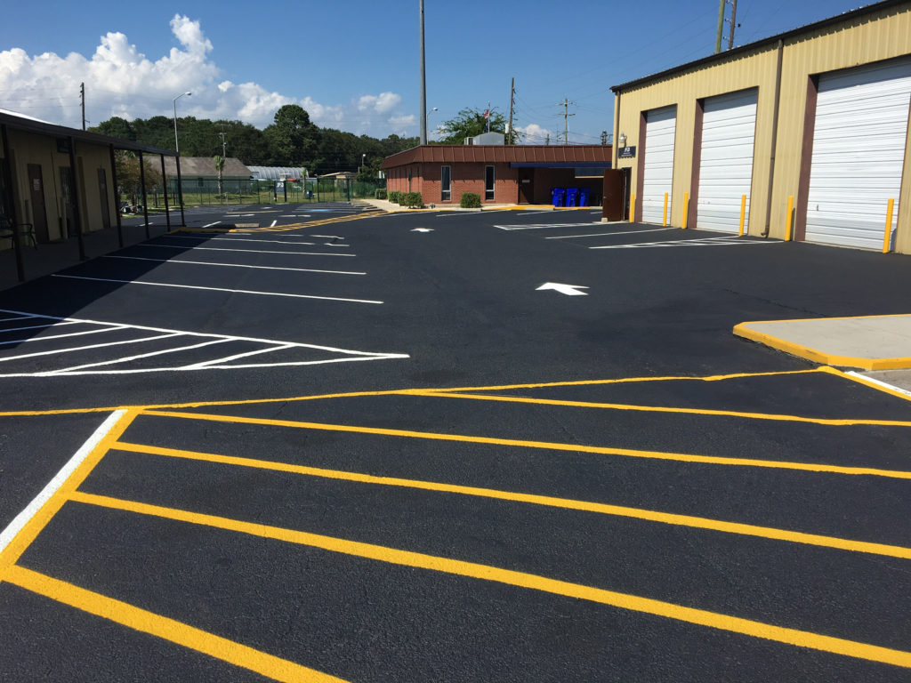 Parking lot with sealcoating and line striping. Lines for parking stalls and directional arrows.